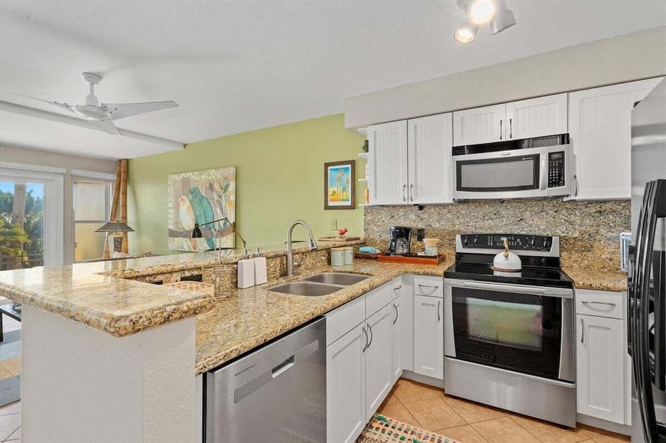 Open kitchen with dishwasher, electric range, microwave, granite countertops, and convenient access to living spaces.