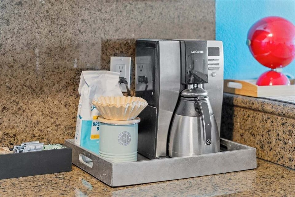 In-unit coffee station featuring a drip coffee maker, filters, and countertop workspace. Convenient setup for enjoying your morning coffee.