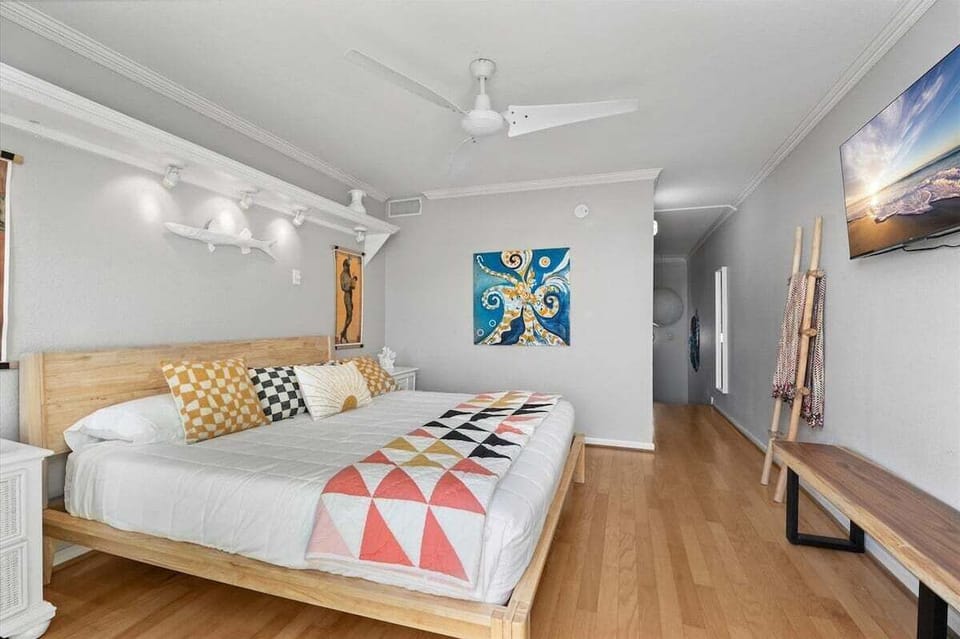 Spacious primary bedroom featuring a king bed, hardwood flooring, ceiling fan, and inviting coastal-inspired furnishings.