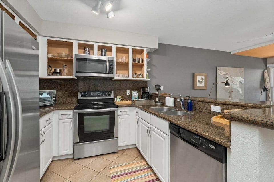 Full kitchen with microwave, oven, stove, dishwasher, granite counters, and stocked cabinetry.
