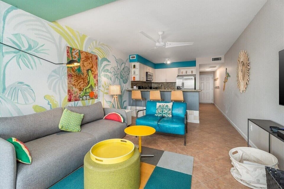 Open-concept living room connecting seamlessly to the kitchen, featuring comfortable seating, coastal-inspired décor, and a spacious layout.