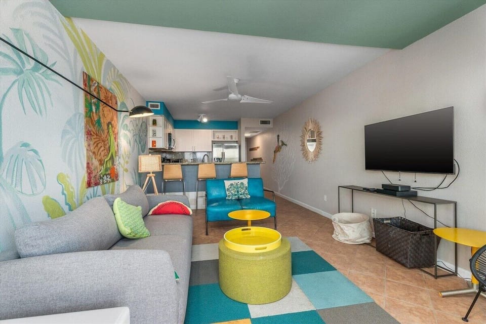 Spacious living area with sectional seating, wall-mounted TV, colorful furnishings, and an open floor plan designed for comfort and entertainment.