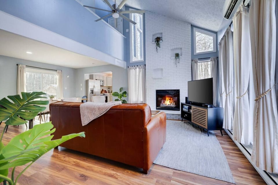 Spacious Living Room with Vaulted Ceiling, Large Smart TV, and Decorative Fireplace- Flooded with Natural Light!
