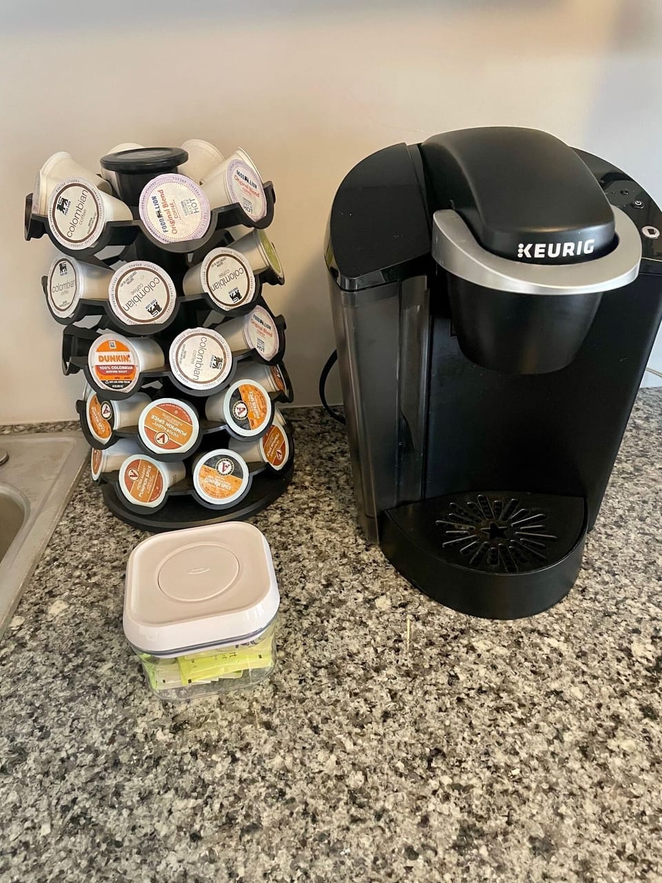 A Keurig coffee maker with complimentary coffee pods, sweetener, and cream