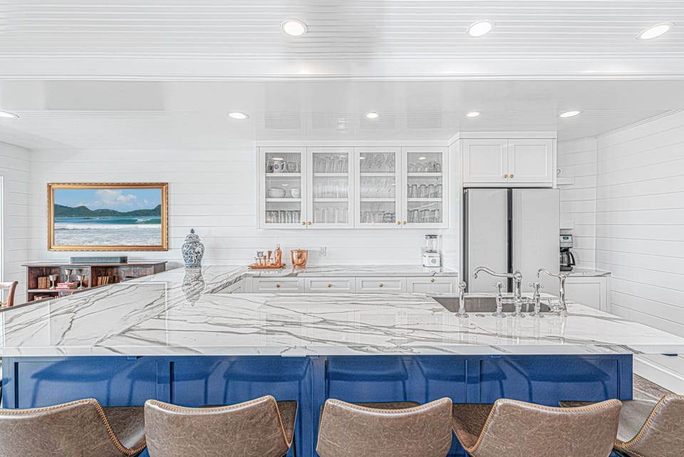 Bright and airy kitchen showcasing sleek countertops, ample prep space, and plenty of barstool seating
                