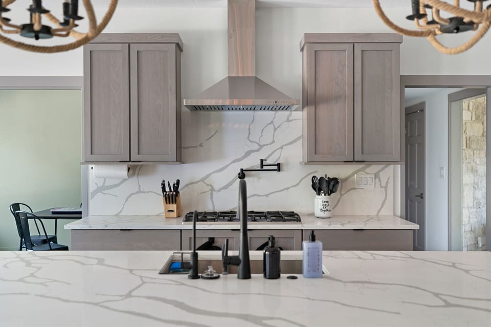 Sleek, contemporary design with a focus on clean lines and neutral tones. Modern kitchen with gray cabinets and white quartz countertops.