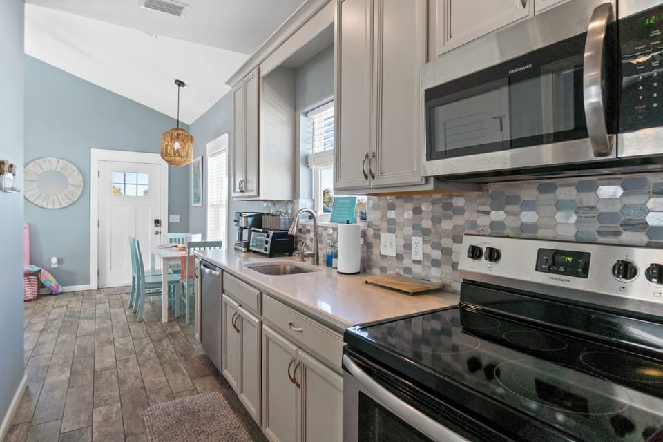 Cook your favorite meals in this modern kitchen featuring stainless steel appliances, sleek countertops, and charming hexagonal backsplash.