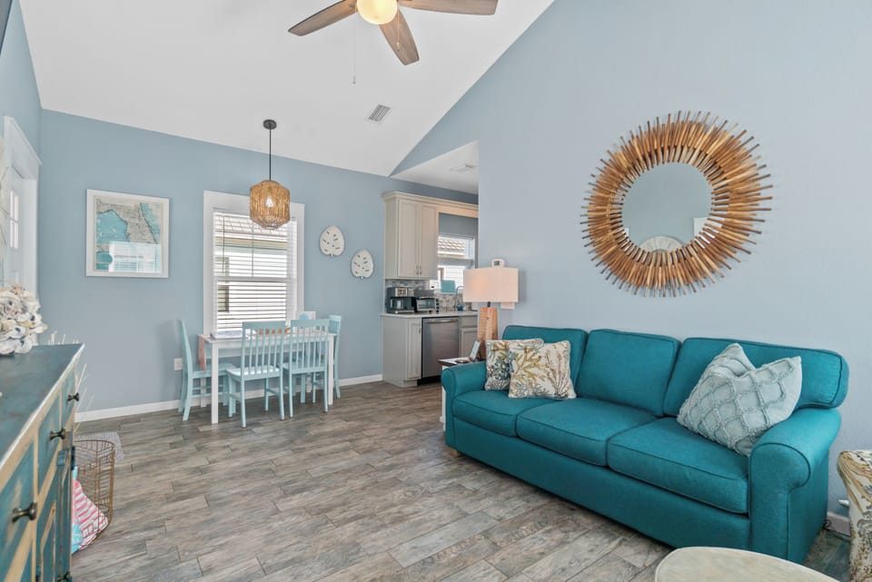 Unwind in your bright, coastal-inspired living space with a comfy teal sofa and open kitchen perfect for family meals.