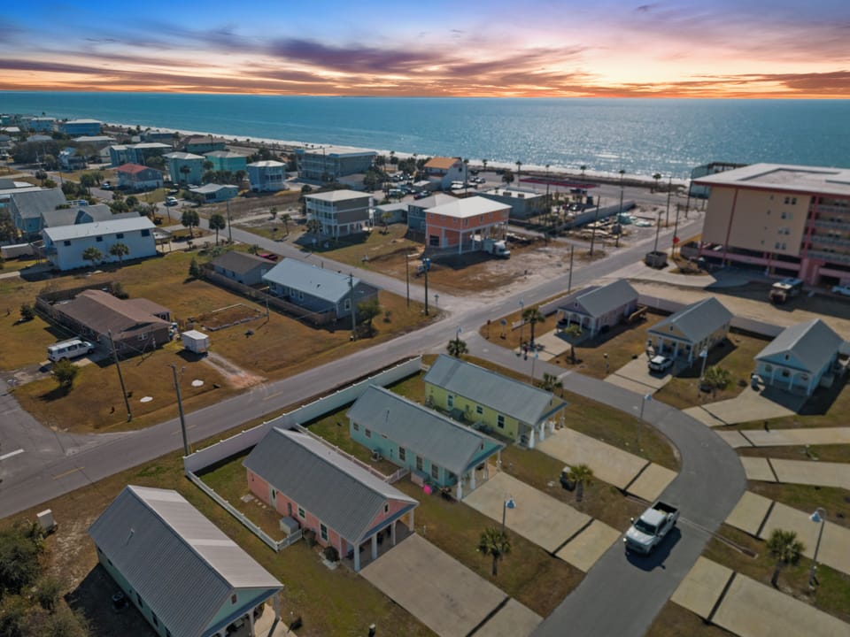 Coastal community with beach access and Gulf waters stretching to the horizon under painted evening skies.
