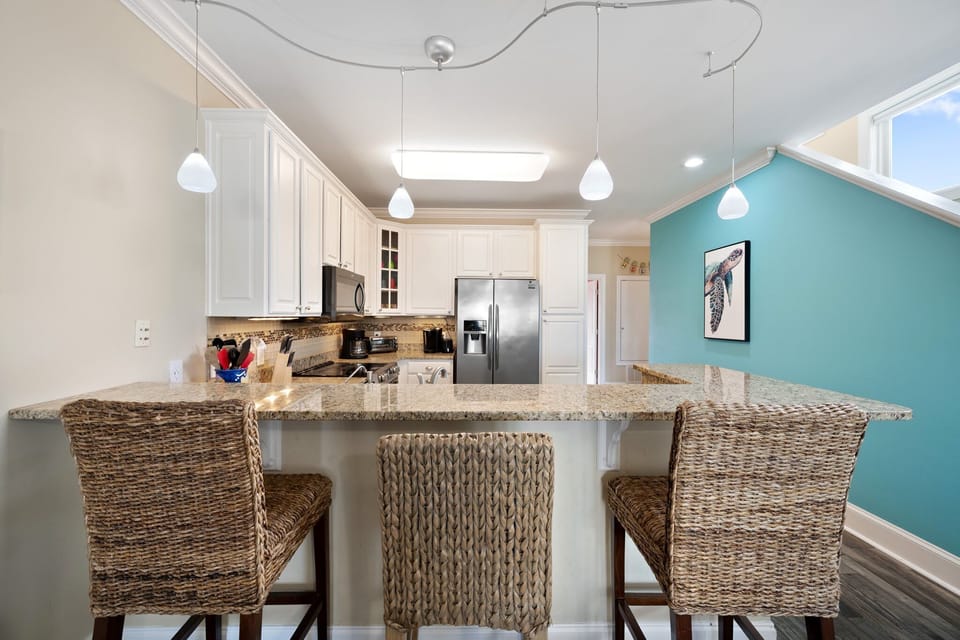 Gather around this stunning granite breakfast bar where your mornings begin with coffee and conversation in this bright, modern kitchen.