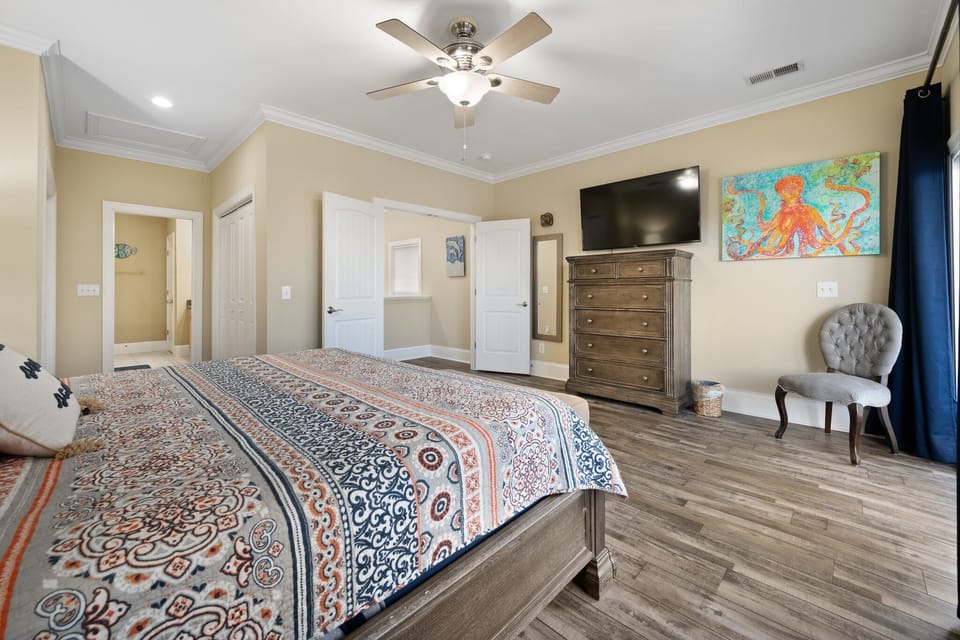 Unwind in your spacious bedroom with rich wood furniture, vibrant coastal art, and a cozy chair perfect for morning coffee.