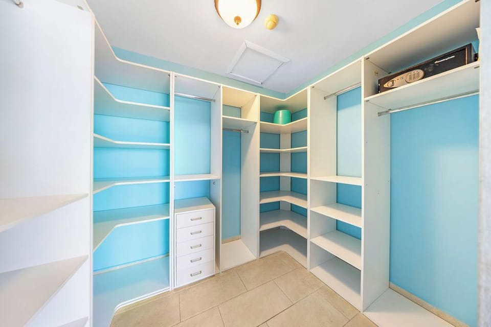 A walk-in closet with a security safe, organized shelving and drawers maximize storage