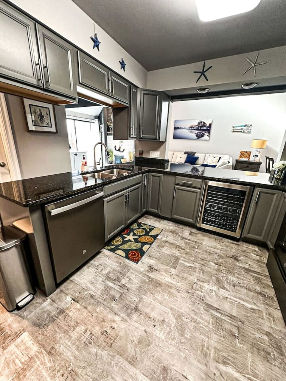 This fully equipped kitchen features sleek gray cabinets, granite countertops, and a wine fridge, offering the perfect blend of style and functionality. The open design allows for seamless interaction with the living area.