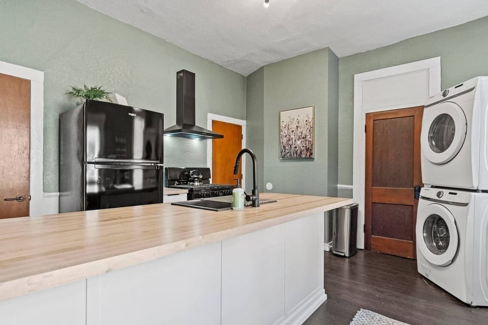 Prep breakfast easily in this fully equipped kitchen, featuring modern black appliances, a butcher block island, and a stacked washer and dryer for longer stays.