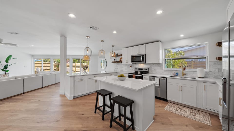 Prepare meals easily in the stunning, fully-stocked, modern kitchen, featuring a central island, coastal decor finishes, and all the amenities needed for your Sarasota vacation.