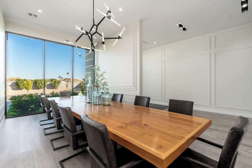 Gather around this handsome wood dining table with seating for eight—where floor-to-ceiling windows frame garden views and sunlight fills your shared meals.