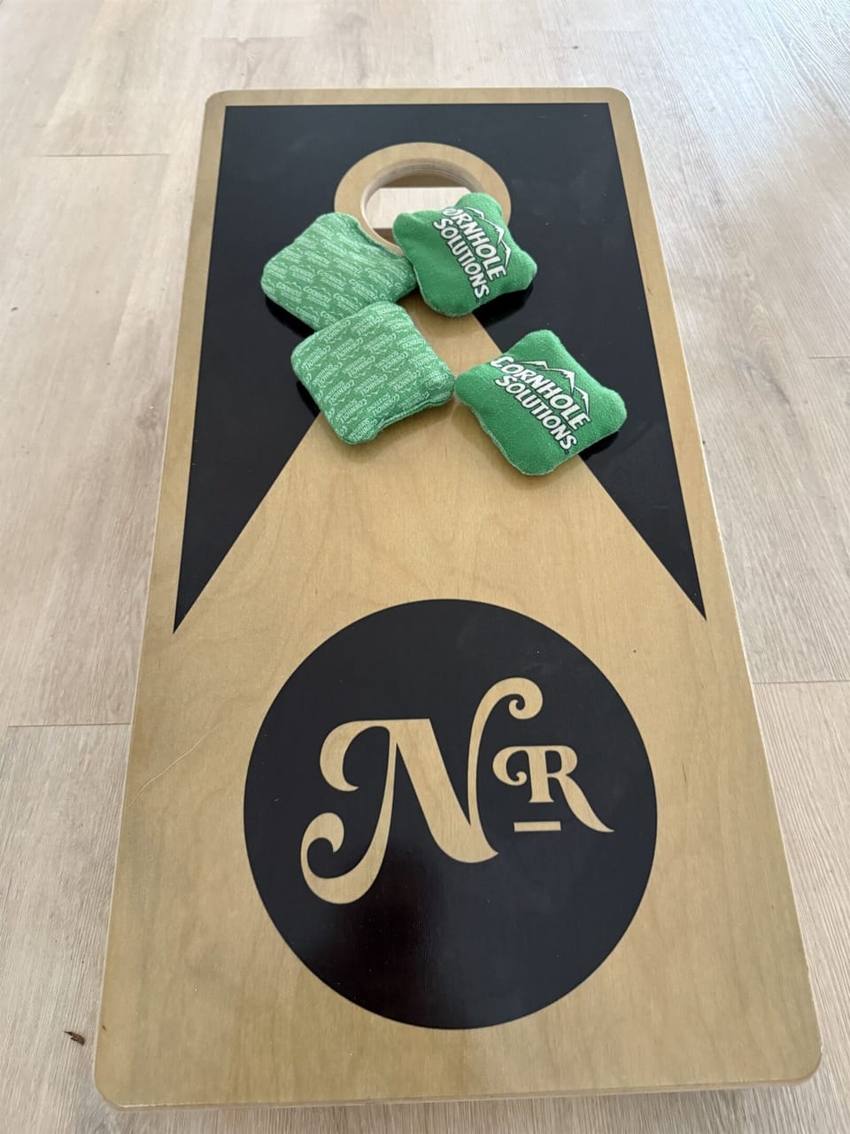 Indoor cornhole in the shared game room — Notestone Reserve branded, separate building a short walk from Yeats
