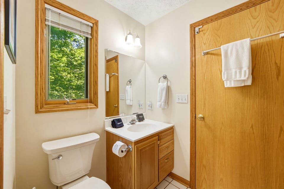 Clean and convenient bathroom with fresh towels, simple essentials, and a peaceful wooded view.