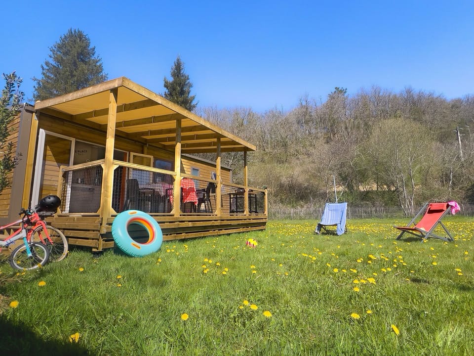 This cozy mobile home features a spacious deck perfect for family gatherings, surrounded by a lush lawn ideal for kids' playtime.