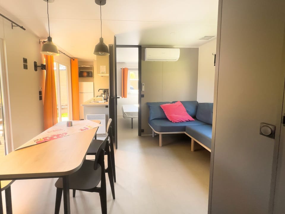 The bright living area, adorned with comfortable seating, flows effortlessly into an outdoor dining area, ideal for family-friendly meals in the fresh air.