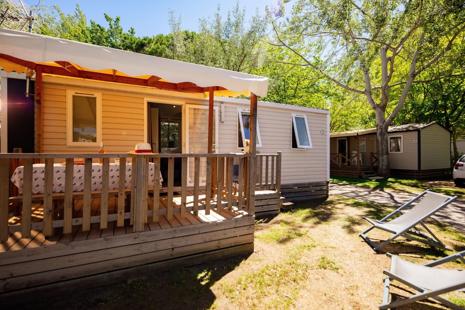 Stay in a cosy mobile home with a wooden terrace, perfect for outdoor relaxation.