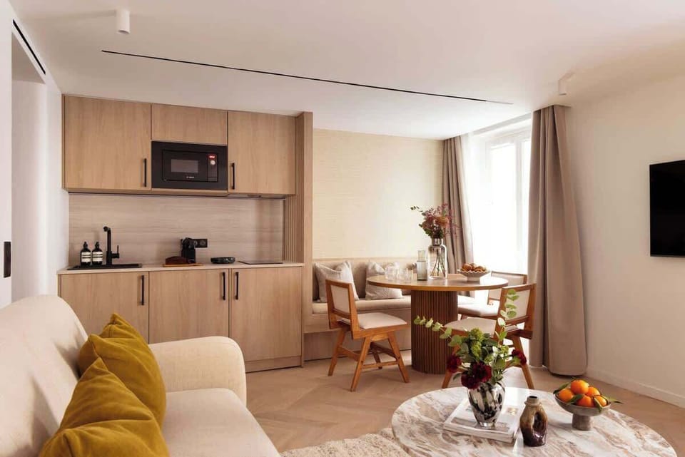 Une belle pièce à vivre dotée d'un canapé convertible, une table d'appoint, une table à manger et une TV.  Cuisine ouverte sur la pièce à vivre et espace repas 