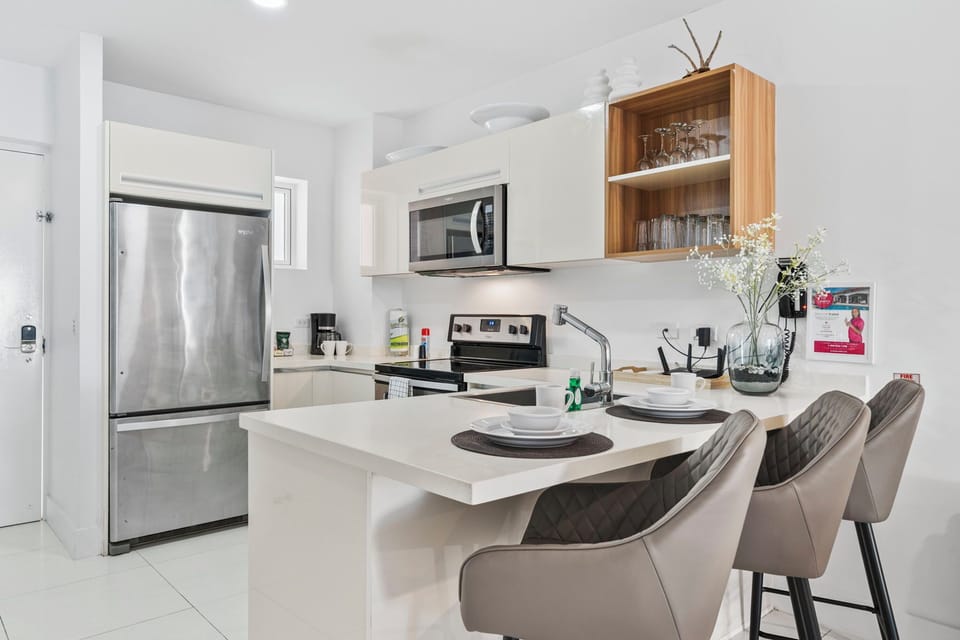 Open-concept kitchen with a spacious breakfast bar for casual dining - Fully equipped with modern appliances and essentials for a seamless cooking experience - Comfortable bar stools provide a perfect spot for morning coffee or evening drinks