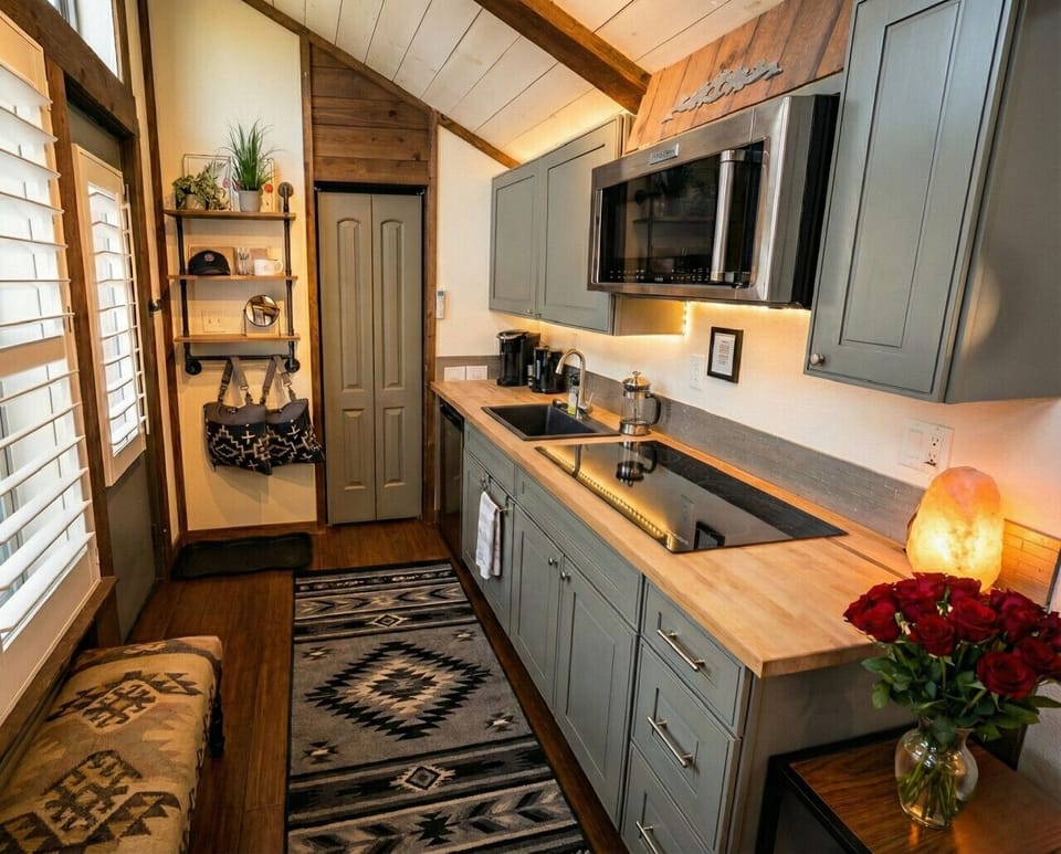 Prepare everything from morning coffee to light meals in the modern kitchenette, complete with a microwave, cooktop, mini refrigerator, sink, coffee maker, cookware, dishes, and essential kitchen supplies.