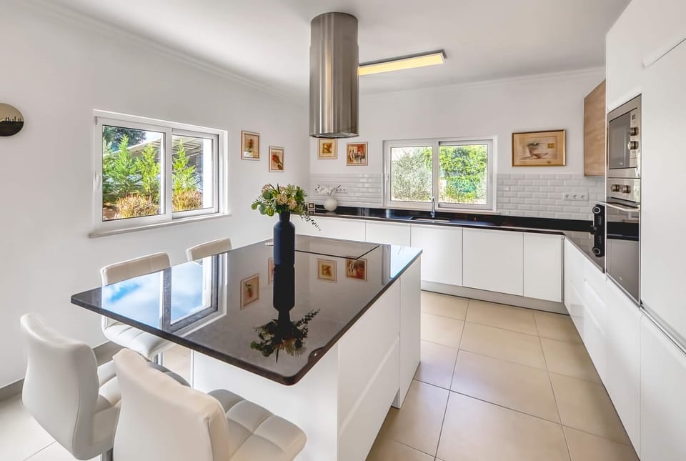 Open-plan kitchen with kitchen island, fridge, microwave, oven and window with garden view