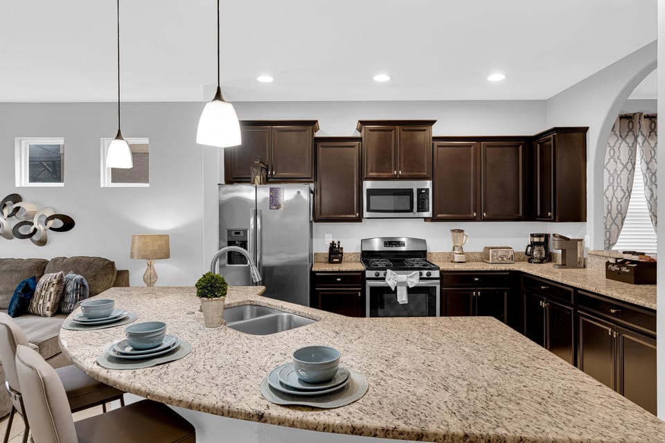 Features stainless steel appliances, a breakfast bar with seating, double sink, microwave, coffee maker, and all essential cookware and utensils.