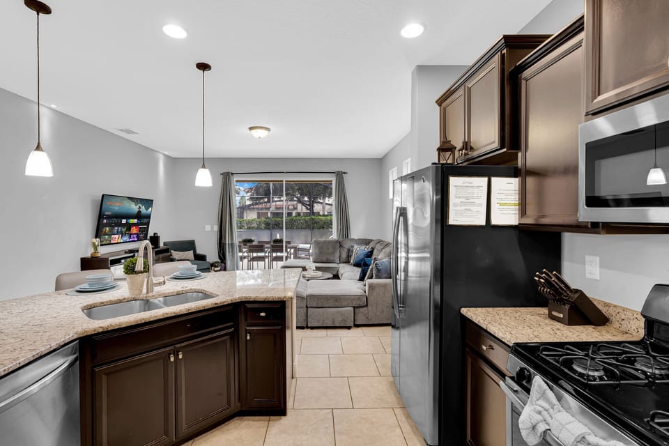 Features stainless steel appliances, a breakfast bar with seating, double sink, microwave, coffee maker, and all essential cookware and utensils.