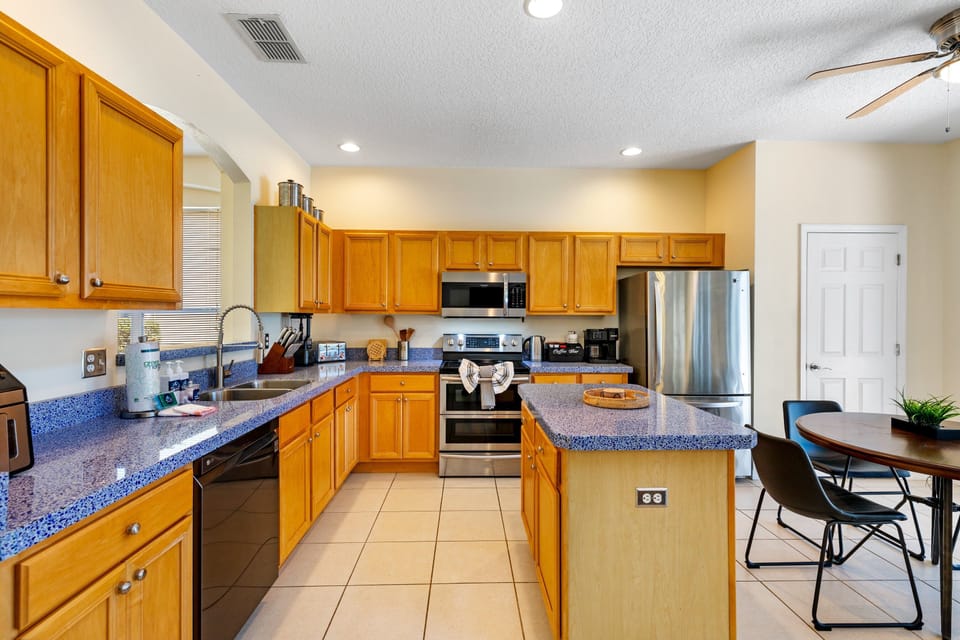 This spacious kitchen features warm wood cabinetry, sleek appliances, a central island