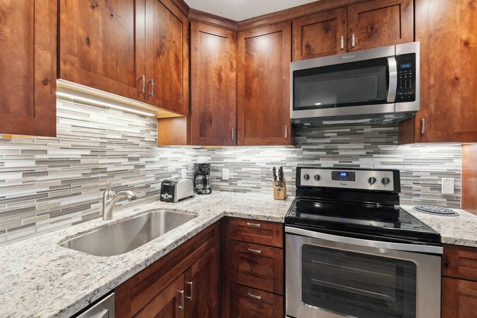 Your fully equipped kitchen features warm wood cabinets, granite counters, and stainless steel appliances—perfect for preparing memorable meals during your stay.