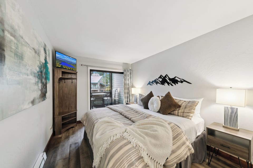 Unwind in your serene bedroom featuring rustic wood touches, mountain art, and your private balcony for morning coffee moments.