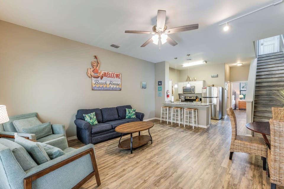 Relax in your stylish beach-themed living space with comfortable seating, modern kitchen, and coastal charm.