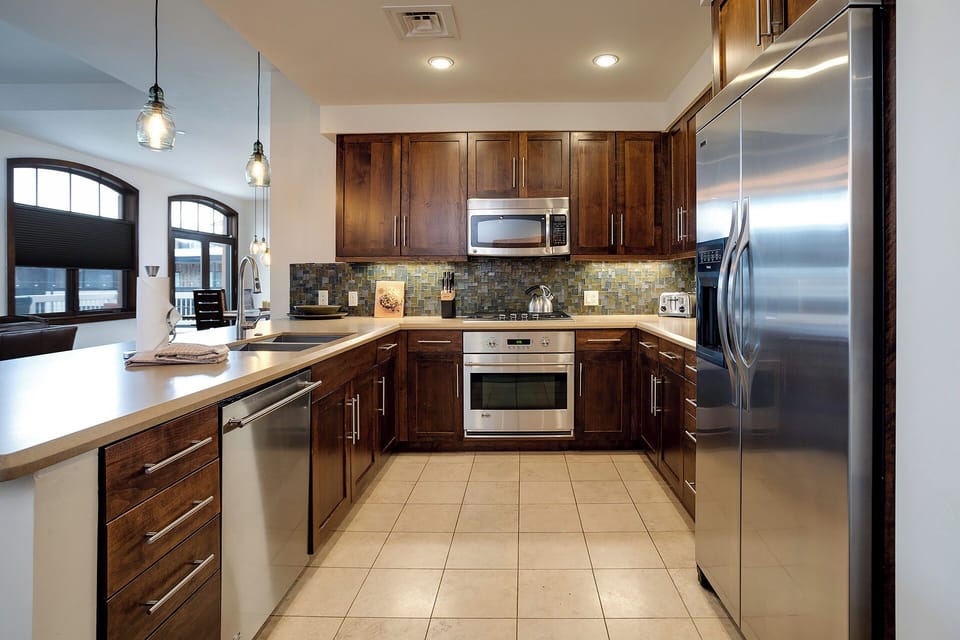 Your gourmet kitchen features rich walnut cabinets, stone countertops, and premium stainless steel appliances for memorable culinary moments together.