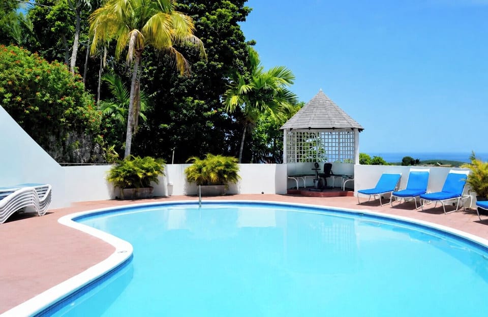 Shared pool surrounded by lush tropical greenery with Caribbean Sea views