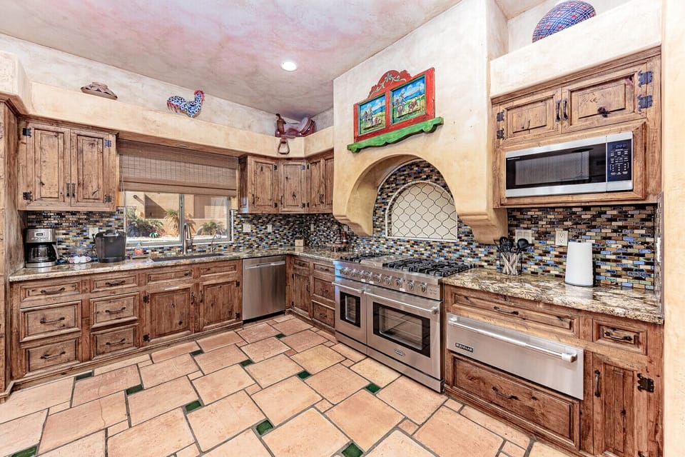 Fully equipped gourmet kitchen with stainless steel appliances, custom wooden cabinetry, and vibrant tile backsplash.