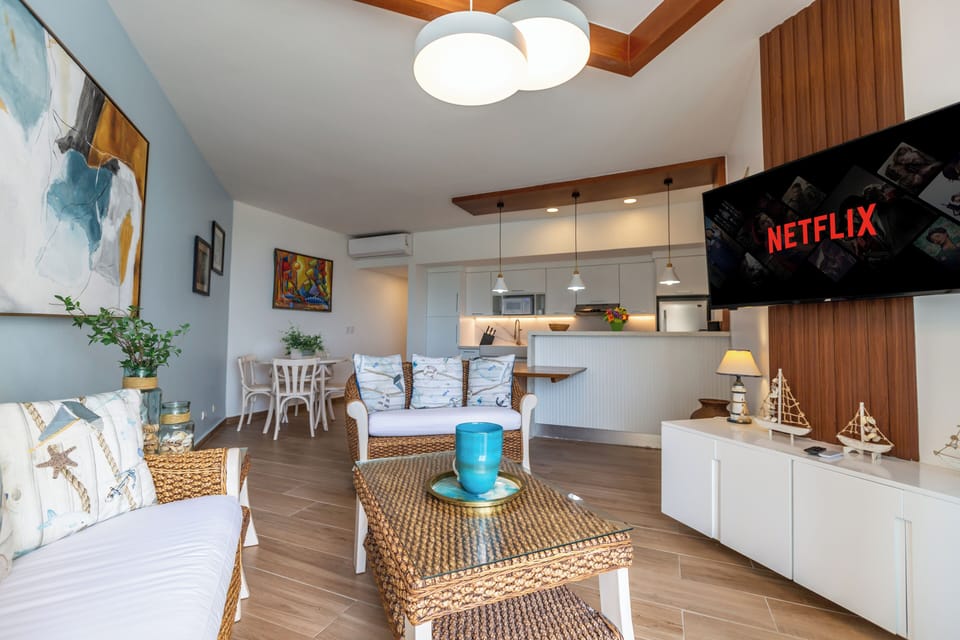 Spacious living room with A/C, a fully equipped kitchen, and a dining table for four.



