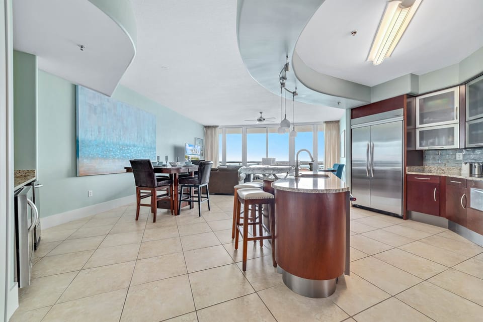 This kitchen showcases a unique blend of contemporary design and functional elegance. The curved island, custom cabinetry, and modern lighting fixtures create a visually appealing and practical space.