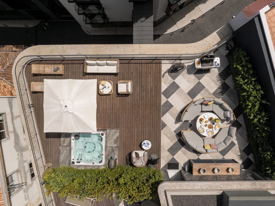An elevated view of the expansive private rooftop terrace, showing the jacuzzi, lounge, grill and outdoor dining areas.