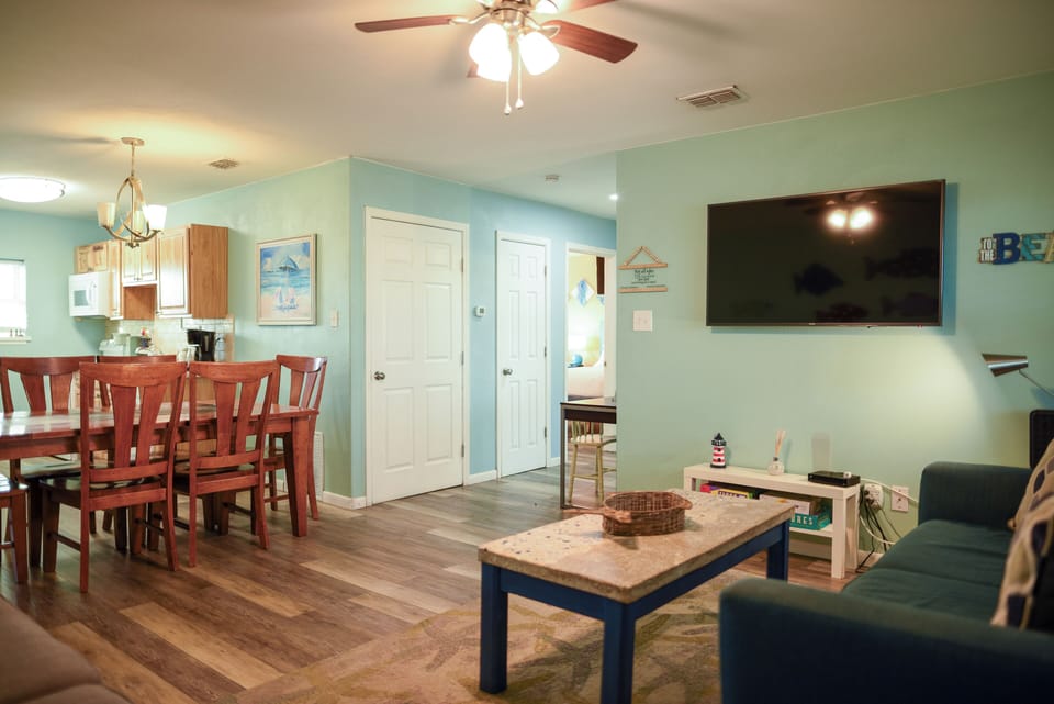 Relax in your spacious open-plan living area with coastal charm, complete with ceiling fan, flat-screen TV, and dining for six.