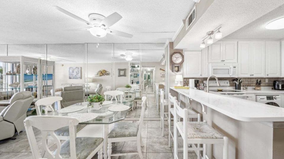 Gather around the glass-top dining table or the breakfast bar with seating for four in this open dining space connected to the kitchen and living area.