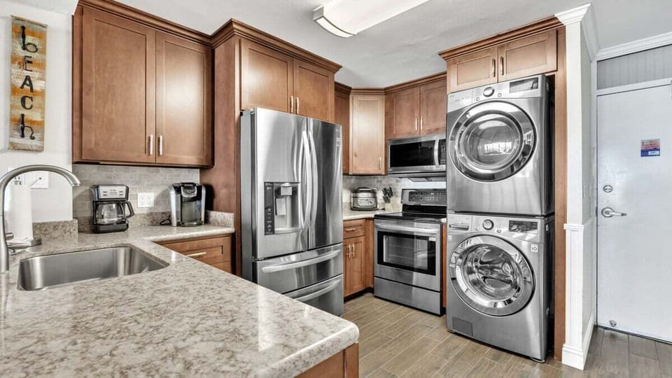 Fully equipped kitchen with stainless steel appliances, stacked washer and dryer, and ample cabinet space—everything you need for cooking and convenience.