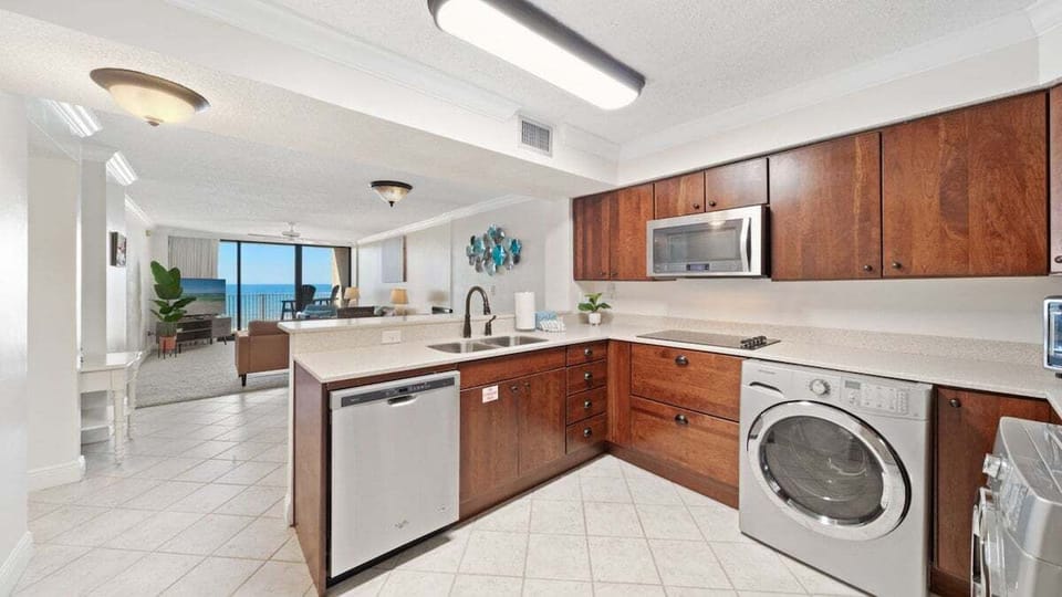 Fully equipped kitchen with stainless steel appliances, in-unit laundry, and ocean views. Open layout flows seamlessly into the bright living area.