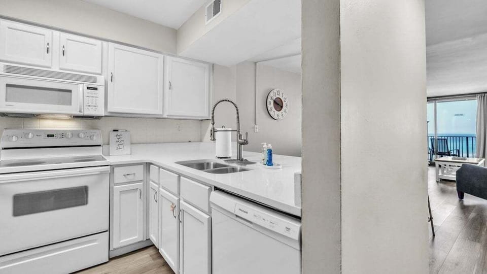 Bright, fully equipped kitchen with sleek white cabinetry, modern appliances, and spacious layout—enjoy ocean views from the sink while you cook or clean.