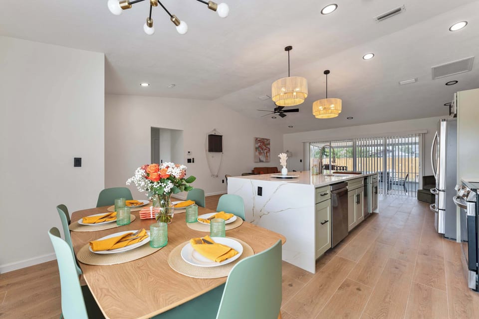 A well-lit dining area featuring a stylish table surrounded by chic chairs, perfect for gatherings. The eye-catching wall design paired with natural light streaming through the window creates a warm, inviting space ideal for both casual meals.