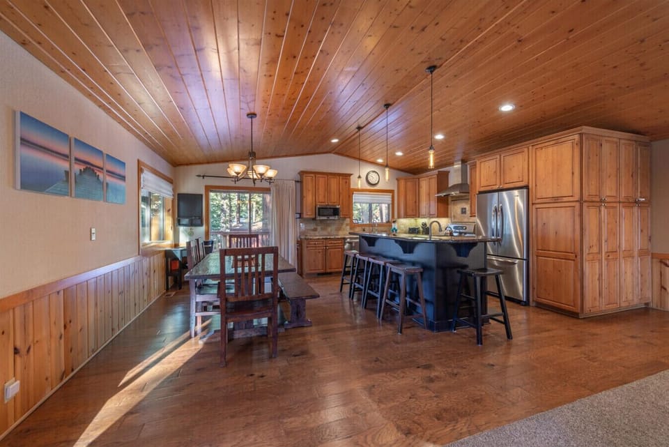 Large open great room (living room, dining area, kitchen) with river rock fireplace, beautiful furnishings, and 60 inch SmartTV.