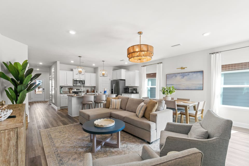 Relax in your stunning open-concept living space where modern elegance meets comfort, featuring stylish furnishings and warm lighting for memorable gatherings.