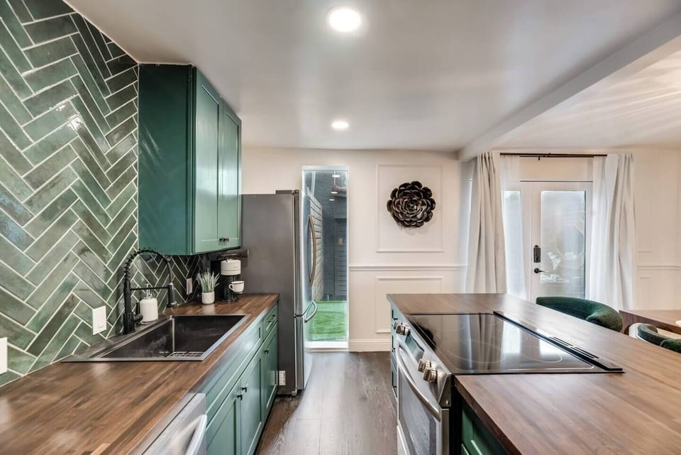 Fully equipped modern kitchen with a sleek island and beautiful green accents, adding an earthy yet sophisticated touch of elegance to your space.